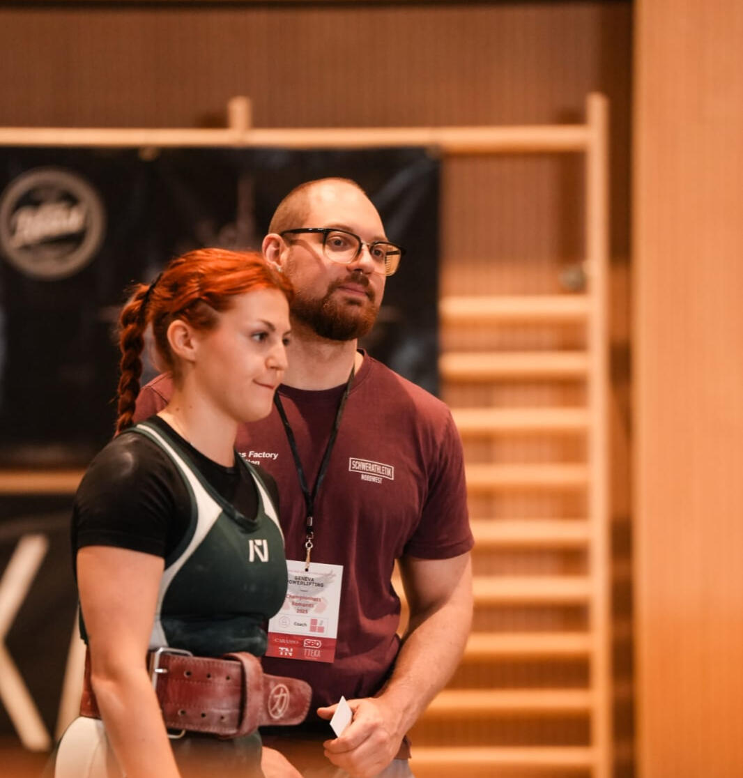 a powerlifting coach working with female clients at a powerlifting competition