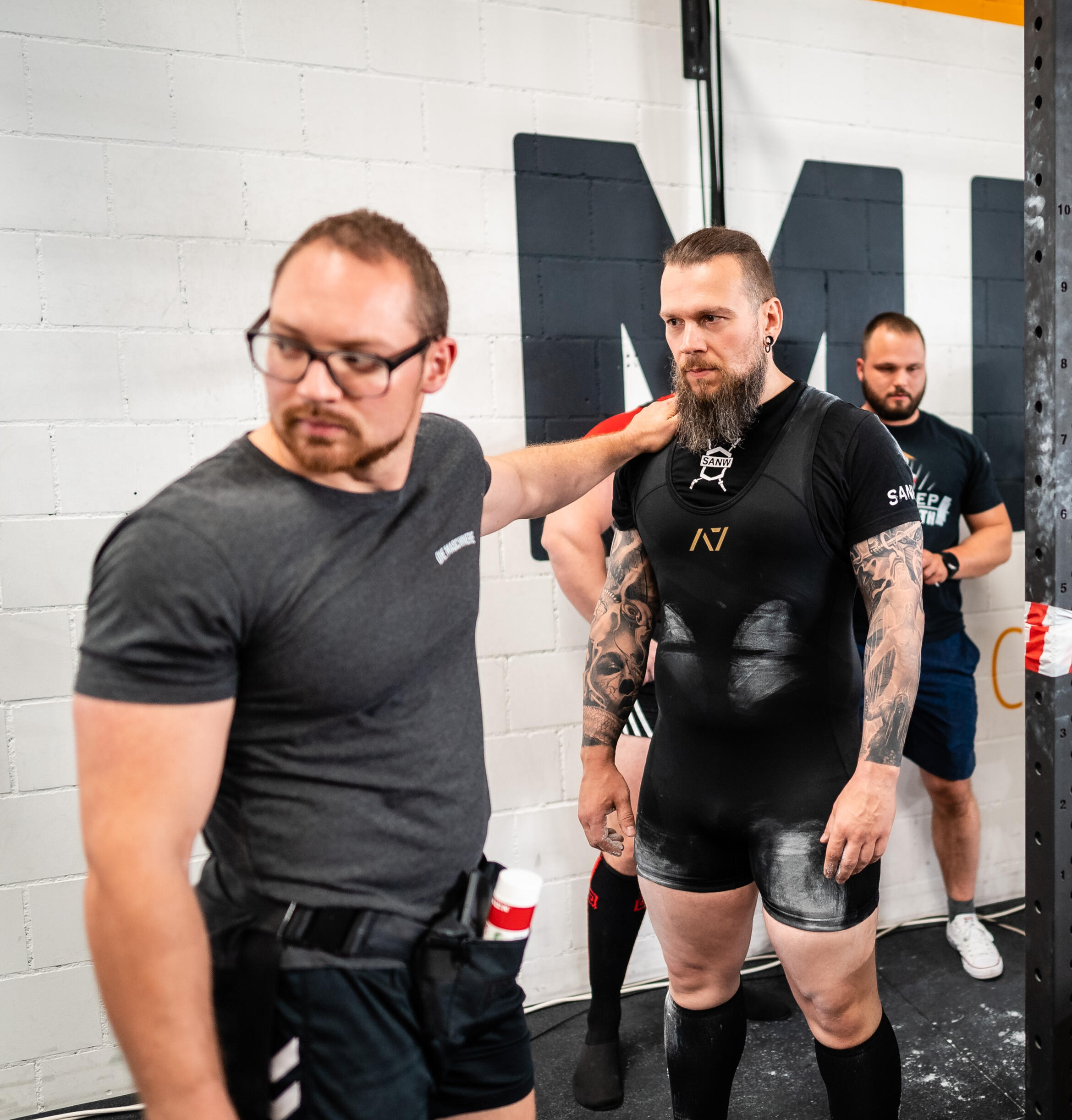 Expert powerlifting coach guiding an athlete moments before stepping onto the competition platform, showcasing peak performance preparation, strength training focus, and competition-day strategy.